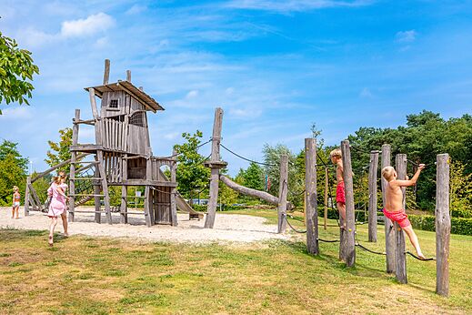 Grote houten speeltuin met klimmende kinderen op camping CAPFUN De Belten in Rheeze.