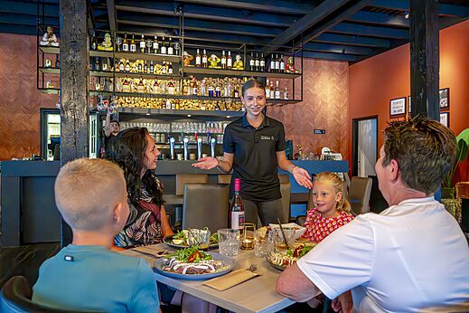 Familie dineert in restaurant met moderne bar op camping CAPFUN De Belten in Rheeze.
