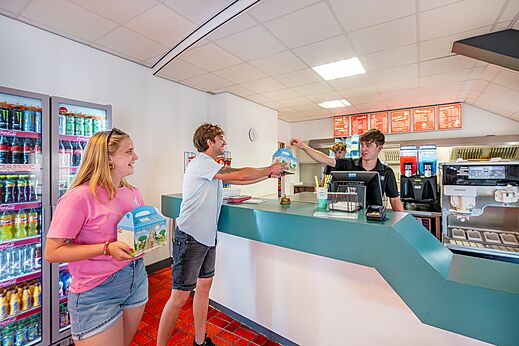 Klant ontvangt bestelling aan de restaurantbalie op camping CAPFUN De Belten te Rheeze.