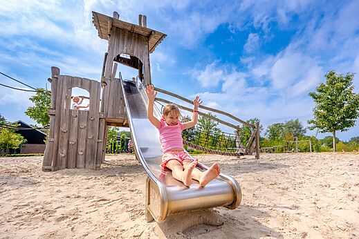 Lachend kind op houten en metalen glijbaan op camping CAPFUN De Belten in Rheeze.