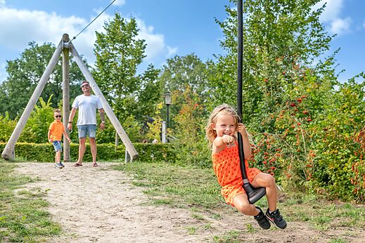 Lachend meisje op tokkelbaan op camping CAPFUN De Belten in Rheeze.