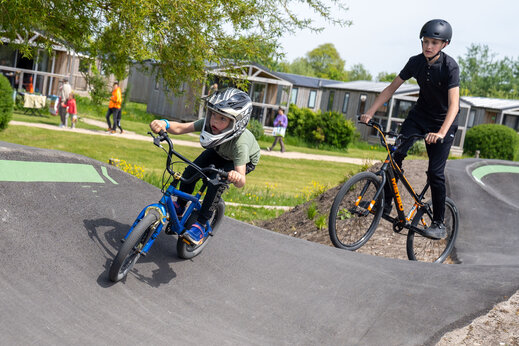 Kinderen fietsen op de pumptrackbaan op camping CAPFUN De Bongerd in Tuitjenhorn.
