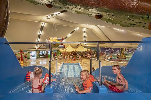 Kinderen op indoor waterglijbaan en zwembad op camping CAPFUN De Bongerd in Tuitjenhorn.