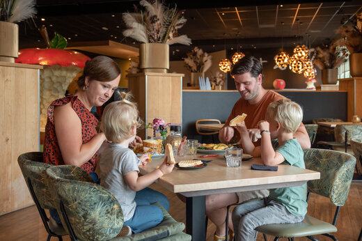 Lachende familie luncht in het restaurant van camping CAPFUN De Bongerd in Tuitjenhorn.