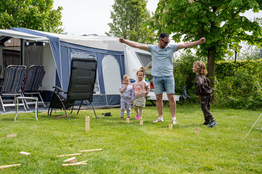 Familie speelt Zweeds kegelspel op een staanplaats bij camping CAPFUN De Bongerd in Tuitjenhorn.