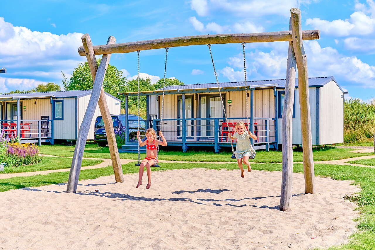 Kinderen spelen op houten schommels, stacaravans op camping CAPFUN De Eikenhof in Paasloo/Oldemarkt.
