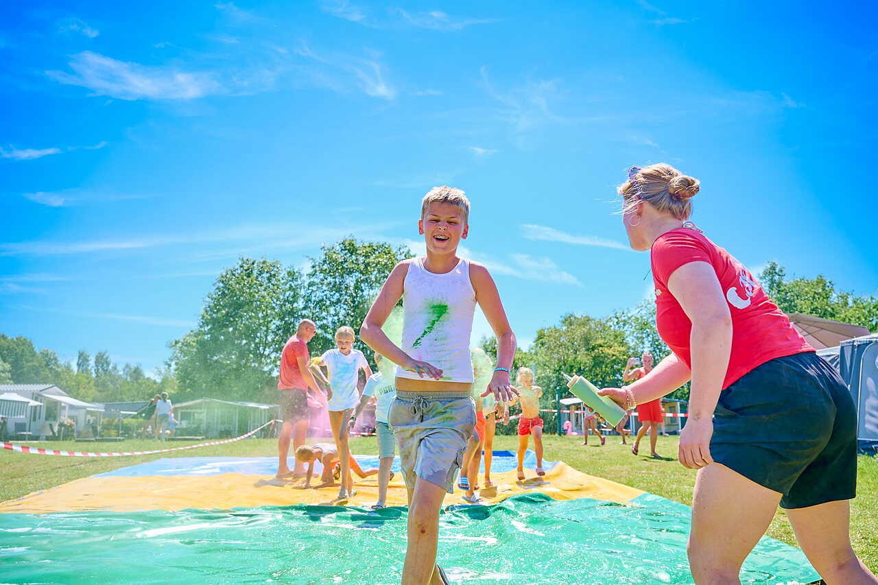 Kinderen en animator op kleurrijke waterglijbaan op camping CAPFUN De Eikenhof.