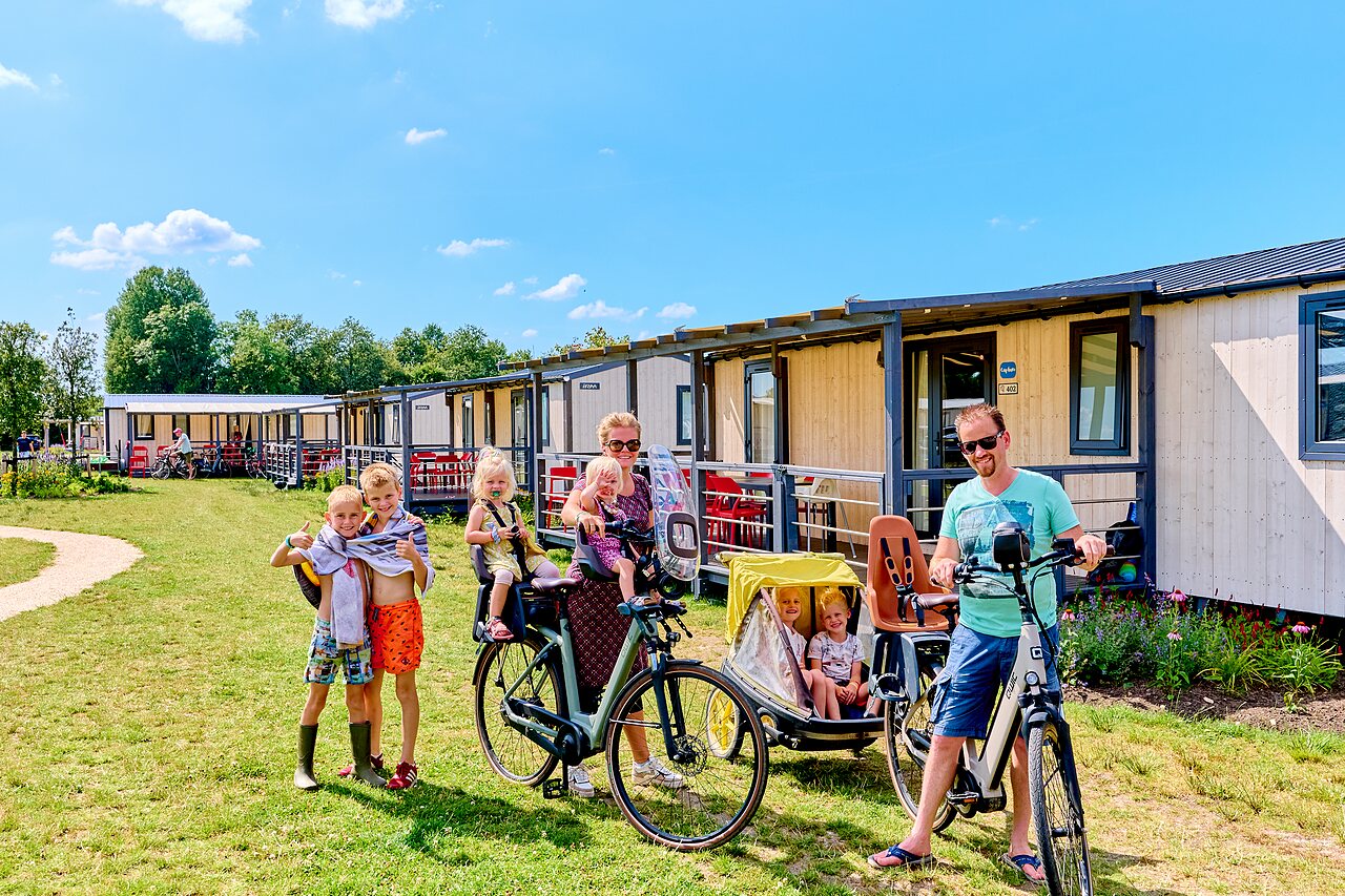 Fietsende familie voor moderne stacaravans op camping CAPFUN De Eikenhof in Paasloo/Oldemarkt.