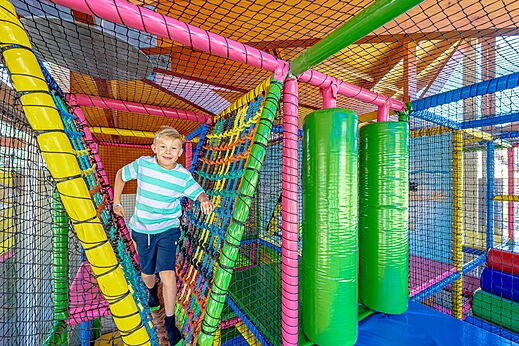 Lachend kind in een kleurrijke indoor speelstructuur op camping CAPFUN De Eikenhof in Paasloo/Oldemarkt.