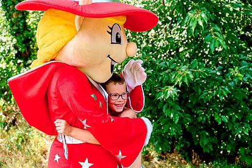 Lachend kind omhelst de mascotte van camping CAPFUN De Eikenhof in Paasloo/Oldemarkt.