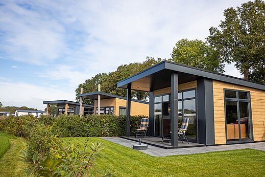Moderne stacaravans met terrassen en stoelen op camping CAPFUN De Eikenhof in Paasloo/Oldemarkt.