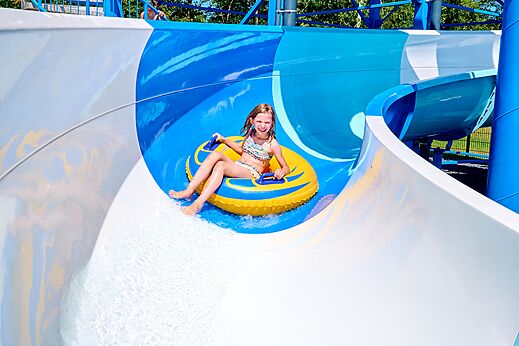 Lachend meisje glijdt van waterglijbaan met band op camping CAPFUN De Eikenhof in Paasloo/Oldemarkt.