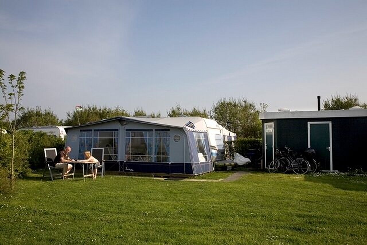 Caravan met voortent, stel op grasveld bij CAPFUN De Pekelinge in Oostkapelle.