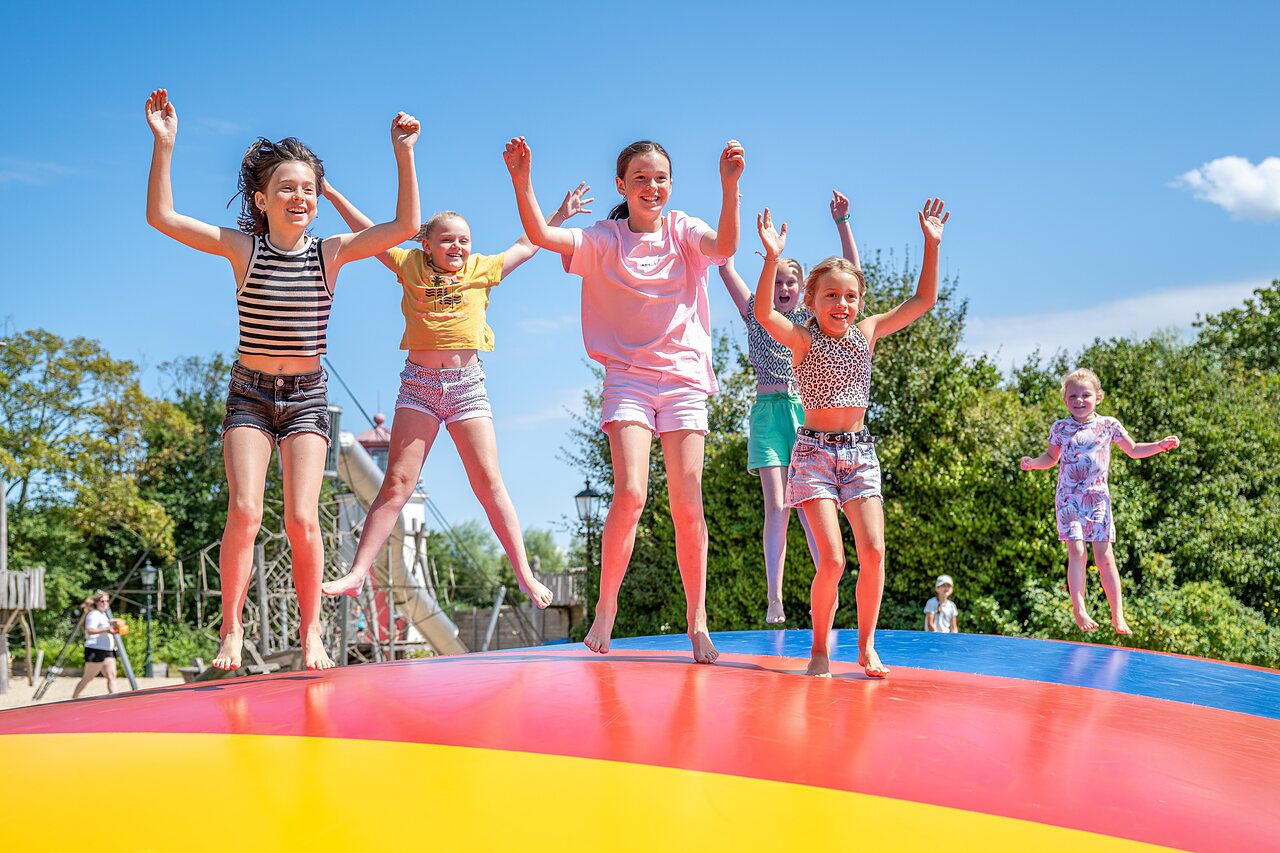 Kinderen springen op reusachtig opblaasbaar springkussen op camping CAPFUN De Pekelinge in Oostkapelle.