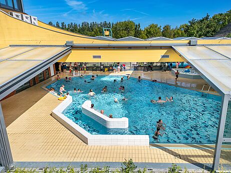 Groot binnen- en buitenzwembad met zwemmers op camping CAPFUN De Pekelinge in Oostkapelle.