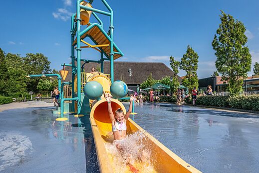 Kind glijdt van een kleurrijke waterglijbaan op camping CAPFUN De Pekelinge in Oostkapelle.