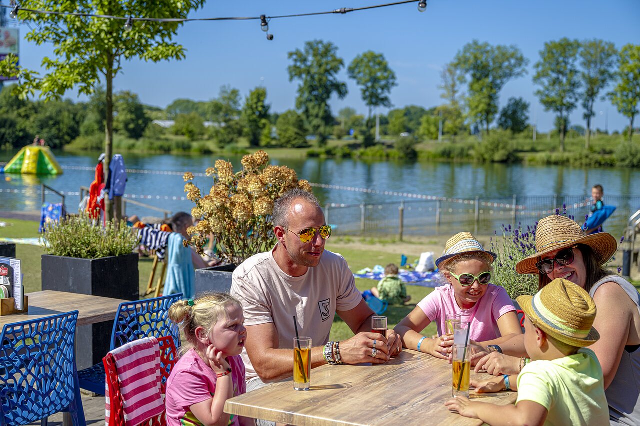 Familie op terras, meer, aquapark op camping CAPFUN De Rotonde in Enspijk.