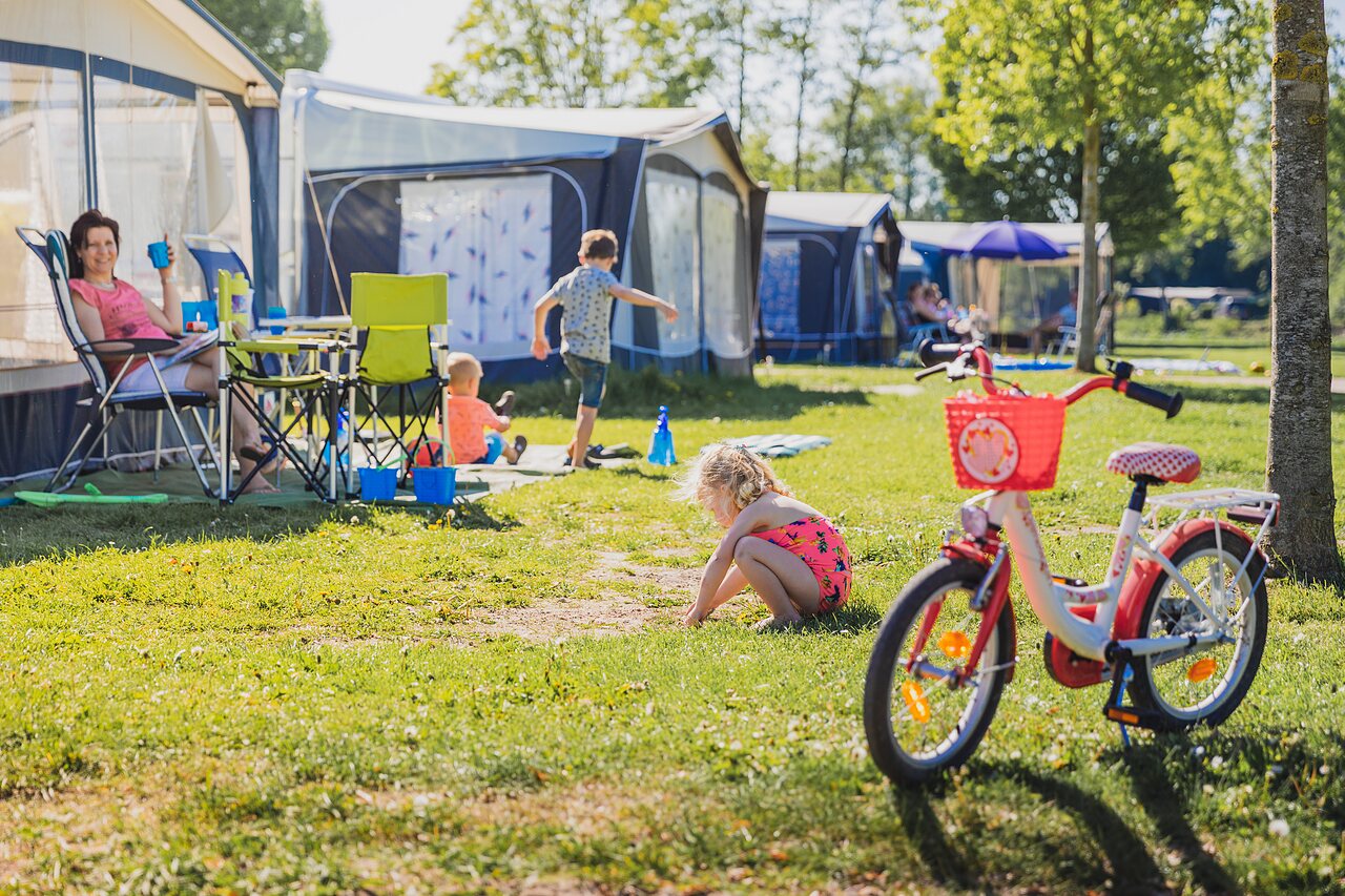 Familiekampeerplaats met spelende kinderen en fiets op camping CAPFUN De Rotonde in Enspijk.