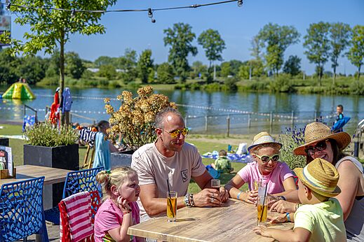 Lachende familie dineert op terras van camping CAPFUN De Rotonde in Enspijk.
