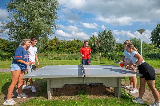 Jongeren spelen tafeltennis buiten op camping CAPFUN De Rotonde in Enspijk.