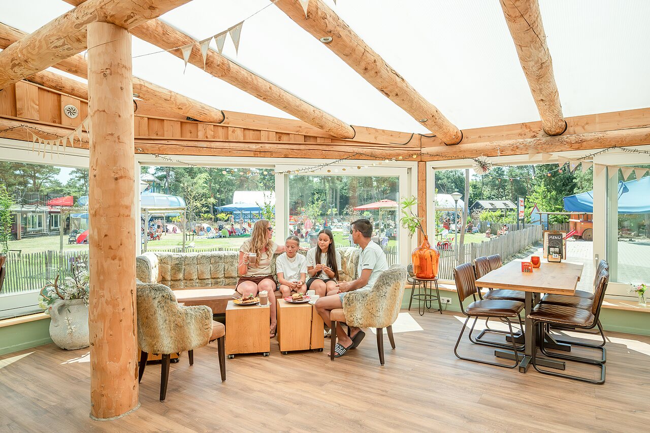 Familie ontspant in het restaurant/bar van camping CAPFUN De Scheepsbel in Doornspijk.