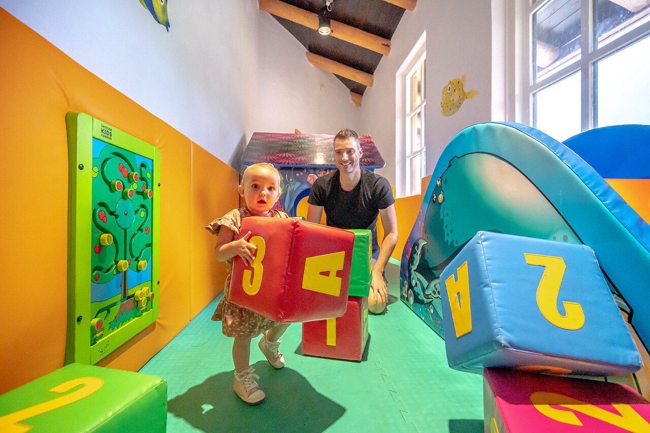 Binnenspeeltuin met baby en volwassene op camping CAPFUN De Scheepsbel in Doornspijk.