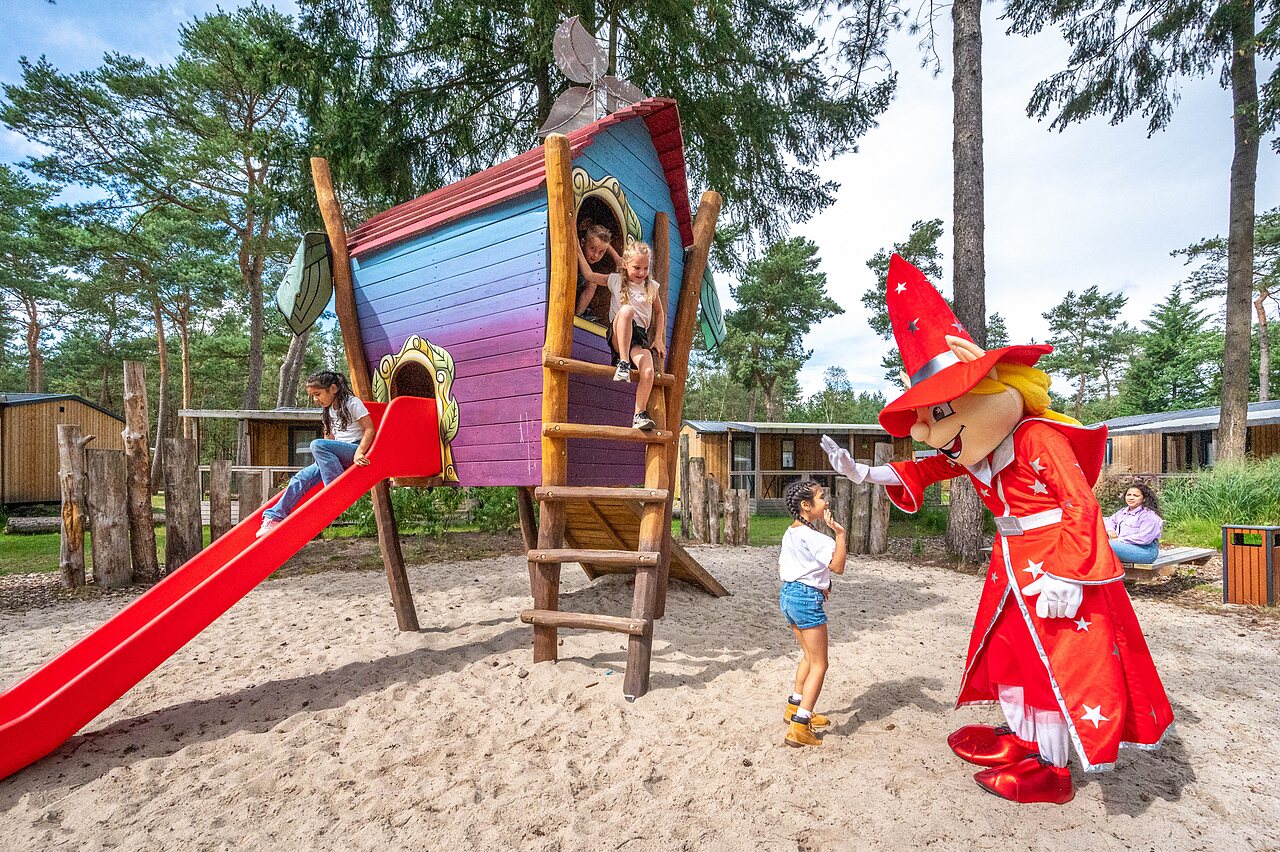 Speeltuin met glijbaan, boomhut en mascotte op camping CAPFUN De Scheepsbel in Doornspijk.