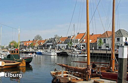 Historische haven van Elburg met boten en traditionele huizen, een bezoek waard.
