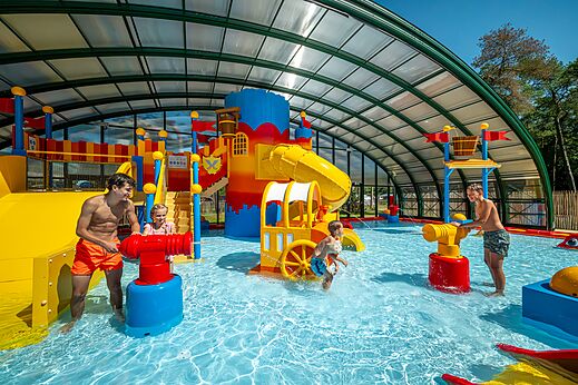 Overdekte waterspeeltuin met glijbanen en waterkanonnen op camping CAPFUN De Scheepsbel in Doornspijk.