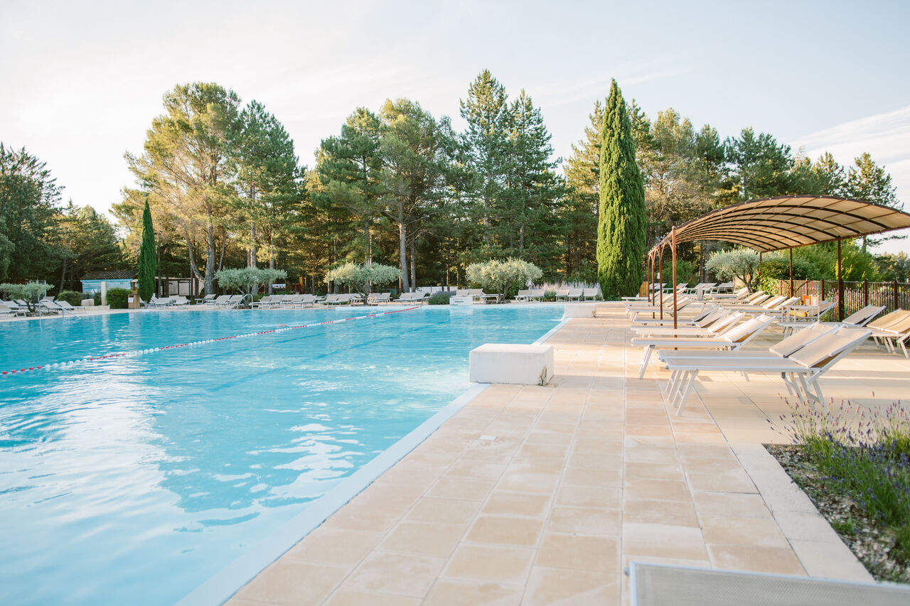 Groot buitenzwembad met ligstoelen en schaduwrijke plek op camping LIBRANOO Naturiste Belezy in B�doin (84).
