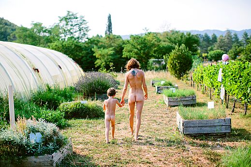 Naturistische familie wandelt door de moestuin van camping LIBRANOO Naturiste Belezy in Bédoin (84).