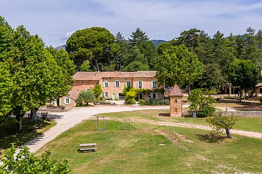 Hoofdgebouw en weelderig groen op camping LIBRANOO Naturiste Belezy in Bédoin (84).