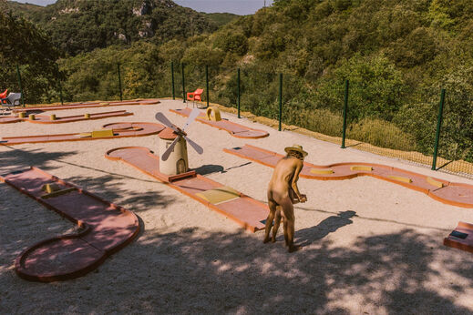 Minigolfbaan met molen, persoon speelt op camping LIBRANOO Naturiste Sabliere.