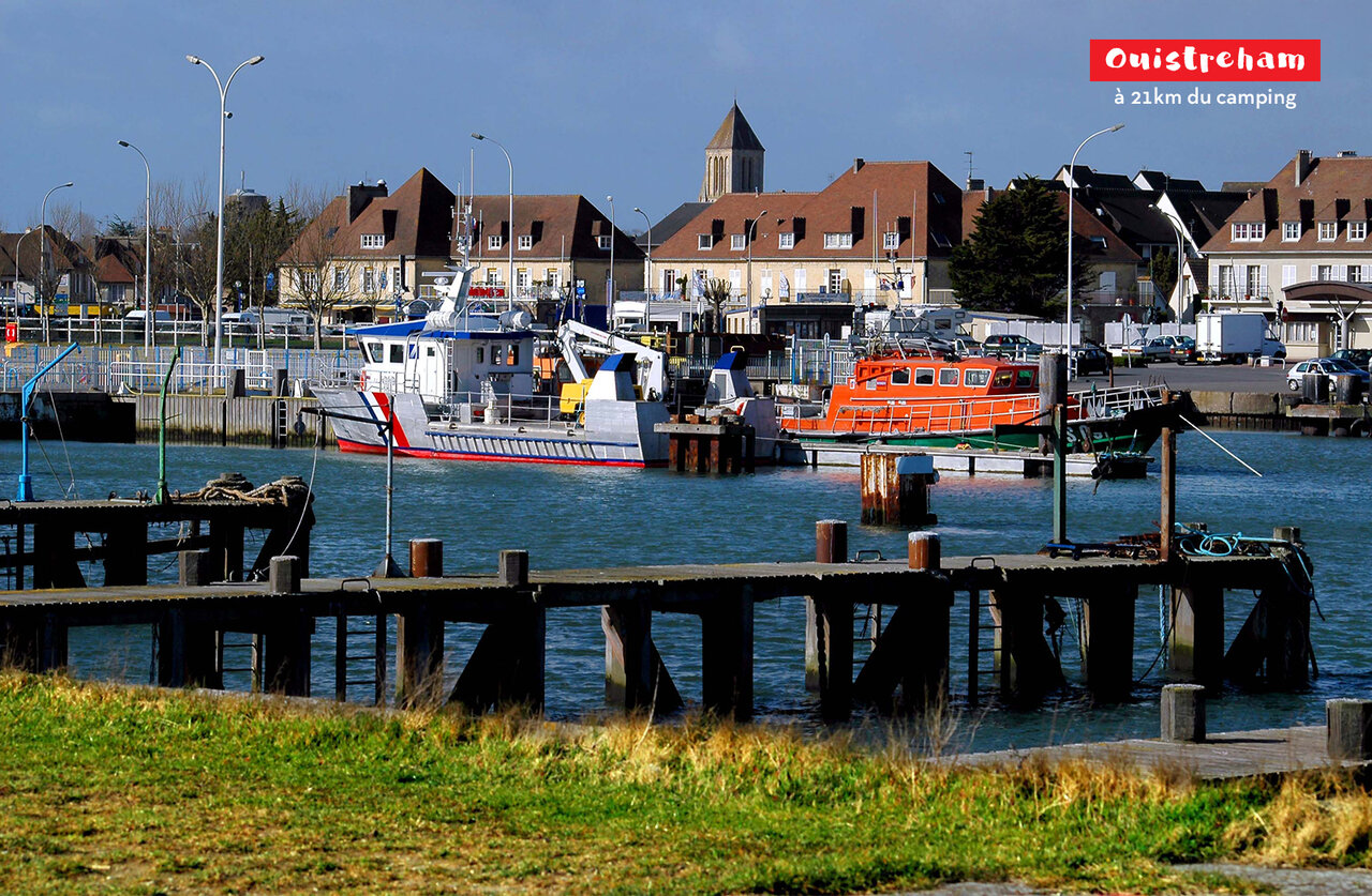 Haven van Ouistreham met boten, huizen en kerktoren in Normandi�.