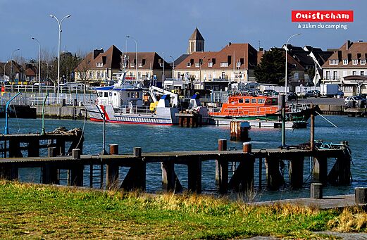 Haven van Ouistreham met aangemeerde boten en traditionele huizen in Normandië.