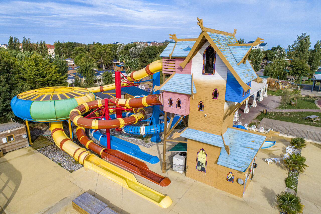 Kleurrijke waterglijbanen en houten speelstructuur op camping CAPFUN Donjon de Lars in Courseulles-sur-Mer.