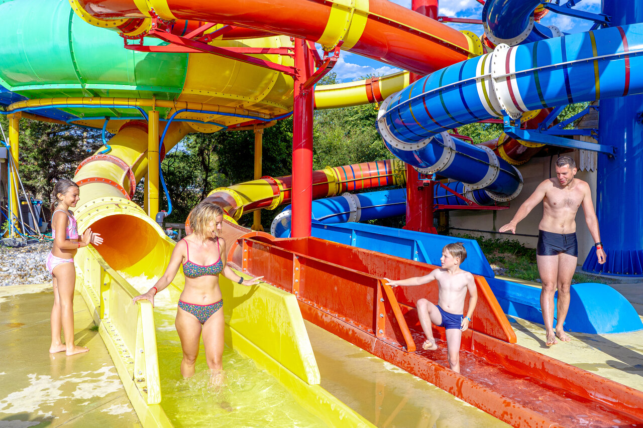 Familie plezier op kleurrijke waterglijbanen bij camping CAPFUN Donjon de Lars in Courseulles-sur-Mer.