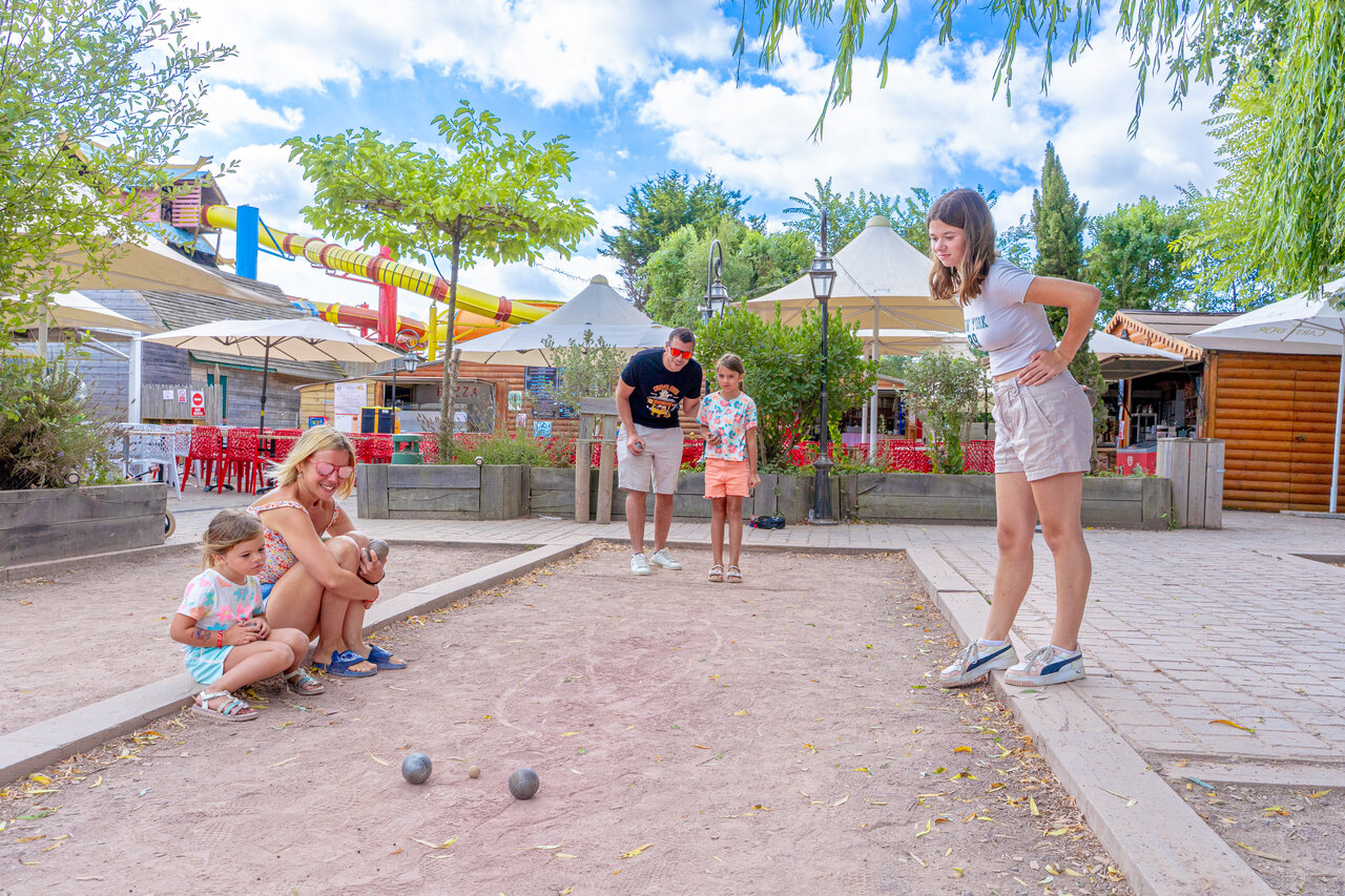 Familie speelt jeu de boules bij waterglijbanen op camping CAPFUN Donjon de Lars.