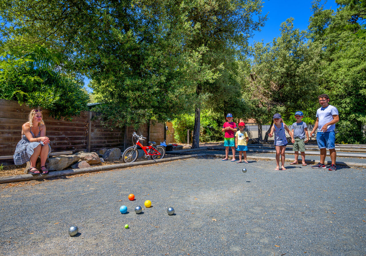 Schaduwrijke jeu-de-boulesbaan, familie spelend op camping CAPFUN Ecureuils in JARD SUR MER (85).