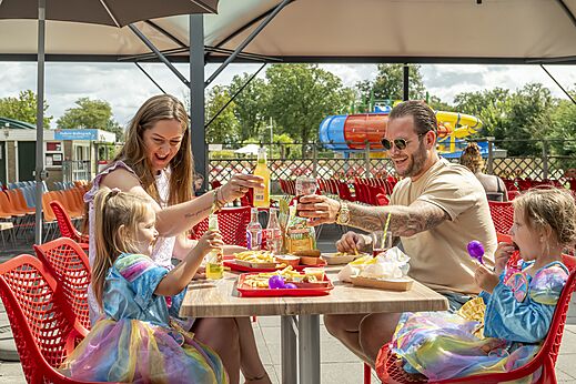 Lachende familie luncht op het restaurantterras van camping CAPFUN Eibernest in Eibergen.