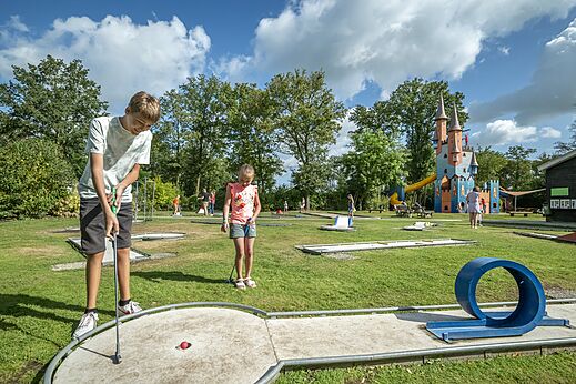 Kinderen spelen minigolf met speelkasteel op camping CAPFUN Eibernest in Eibergen.
