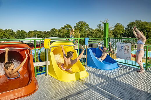 Kleurrijke waterglijbanen en kinderen die plezier hebben in het zwembad op camping CAPFUN Eibernest in Eibergen.