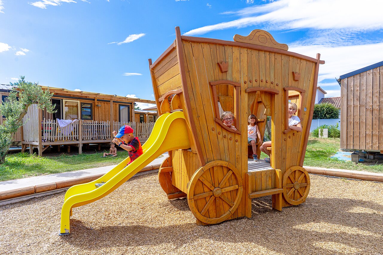 Kinderen op houten koets speeltuin, glijbaan op camping VAGUES OCEANES Elys�e in Le Grau du Roi (30).