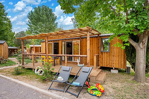 Houten Mobil-home met overdekt terras en stoelen op camping CAPFUN El Moli in Elne (66).