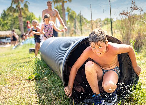 Kind komt uit watertunnel, waterspel op camping CAPFUN El Moli in Elne (66).