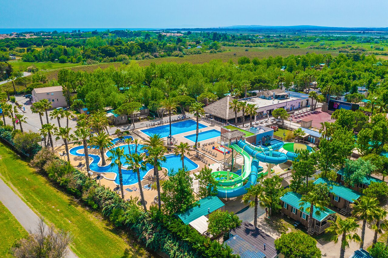 Groot waterpark met glijbanen en palmbomen op camping CAPFUN Emeraude in Portiragnes (34).
