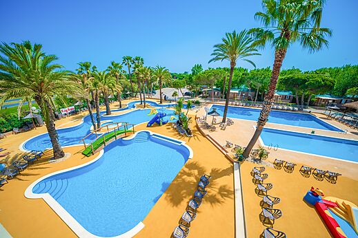 Groot buitenzwembad met glijbanen en palmbomen op camping CAPFUN Emeraude in Portiragnes (34).