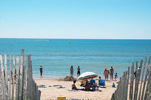 Zandstrand met zwemmers en parasol op camping CAPFUN Emeraude in Portiragnes (34).