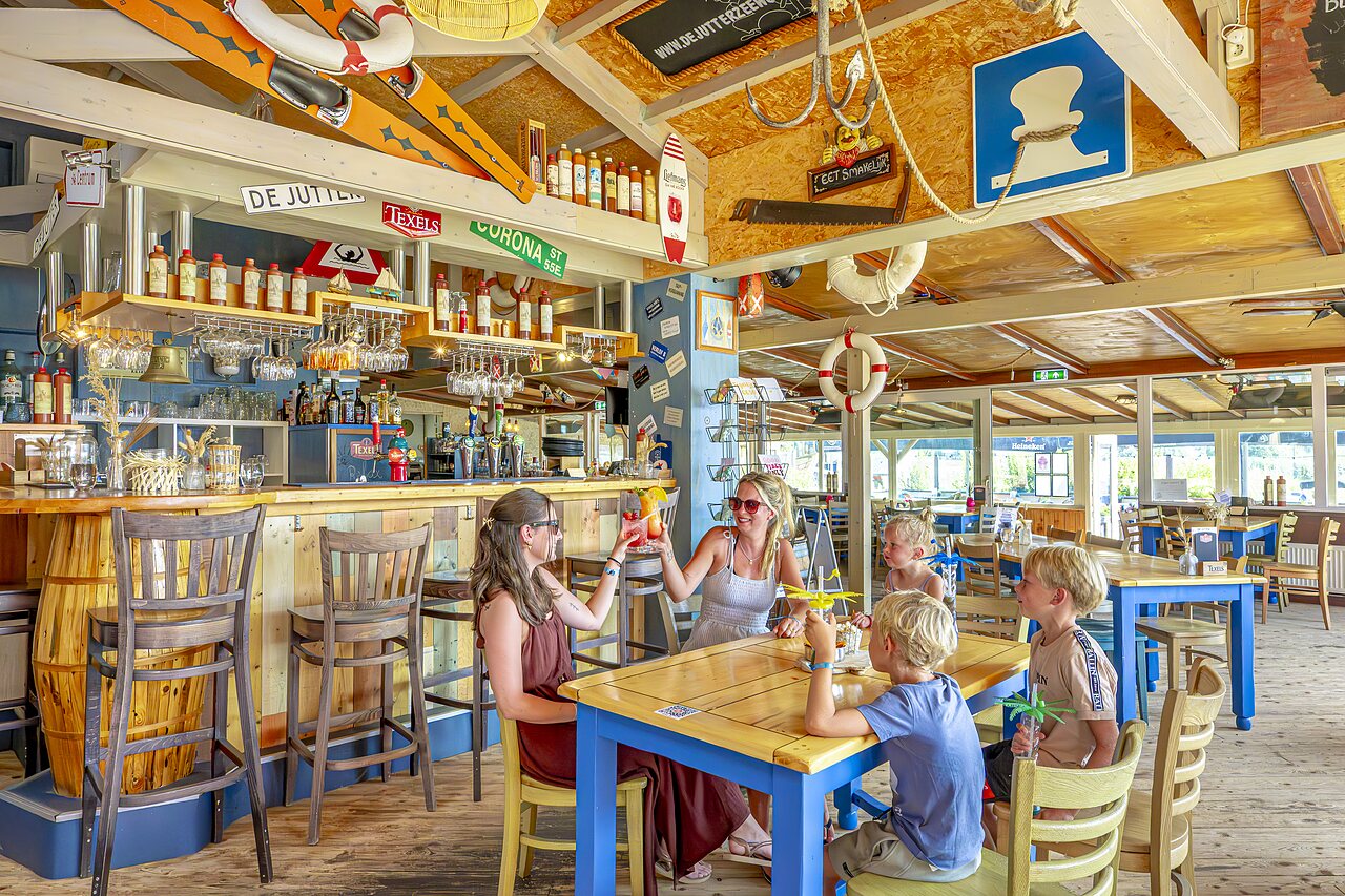 Bar en familierestaurant met volwassenen en kinderen op camping CAPFUN Erkemederstrand in Zeewolde.