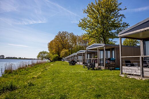 Moderne stacaravans aan het water, omringd door groen op camping CAPFUN Erkemederstrand in Zeewolde.